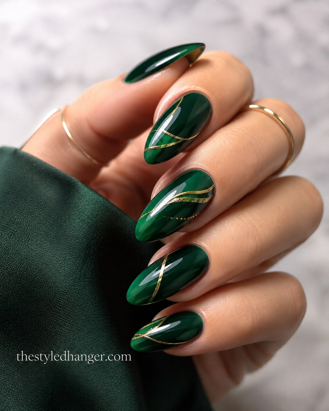 Deep emerald with a gold swirl accent nail shows how moody green nail shades wear for evenings.