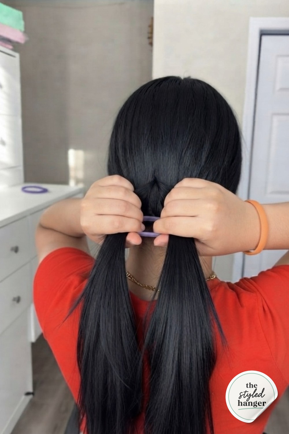 Splitting the ponytail above the tie to prepare for the signature hair tie ponytail hack tuck
