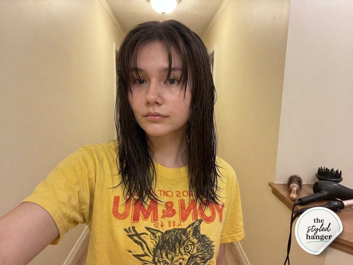 Damp, flat medium length wolf cut hair before styling begins in a cream-toned hallway mirror selfie