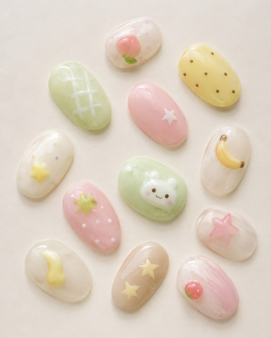 Pastel press-on nail set for spring featuring bear, banana, strawberry, and star charm details