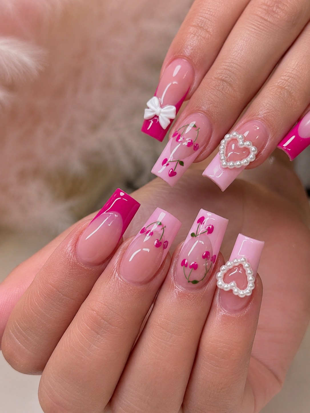 Pink and hot-pink two-tone coffin nails with cherry art, a bow, and a pearl heart charm