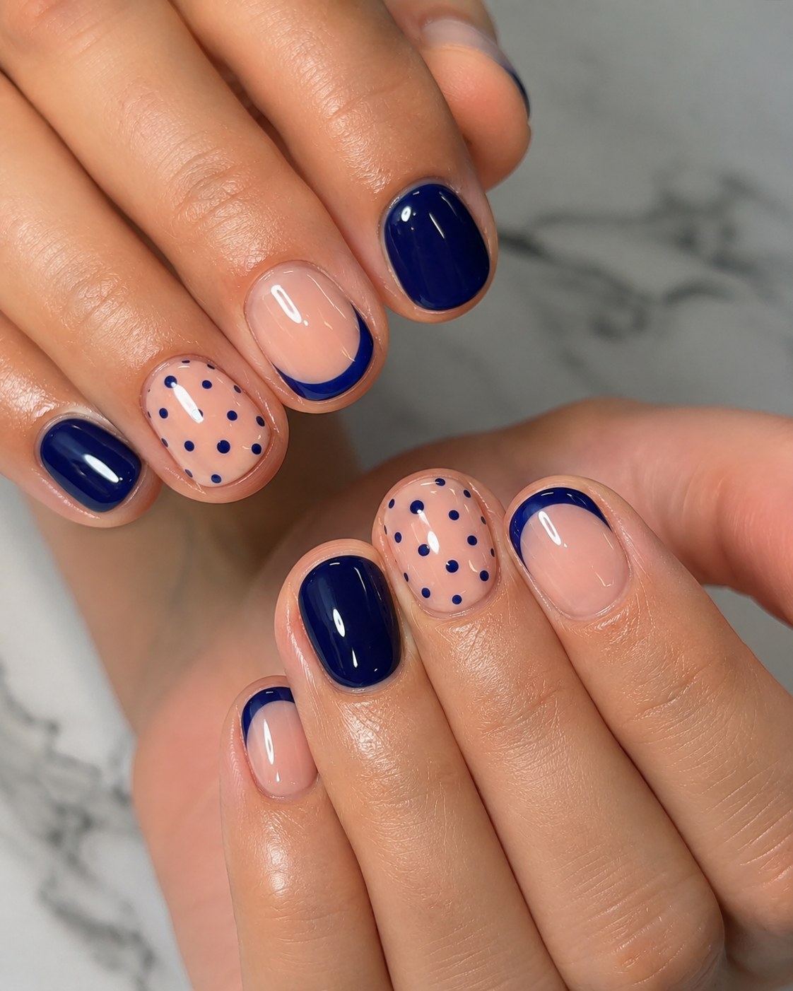 Navy half-moon manicure with polka dot accents on short natural nails