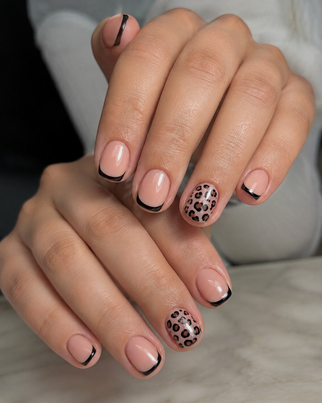 Short natural nail design with black French tips and a leopard print accent nail