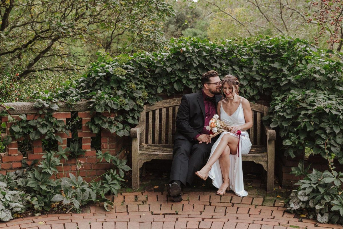 Couple seated on garden bench elopement pose