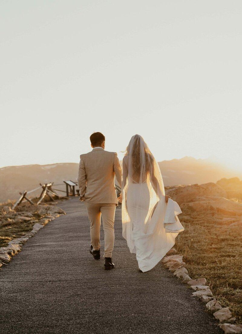 Newlyweds walking at sunset elopement photography pose