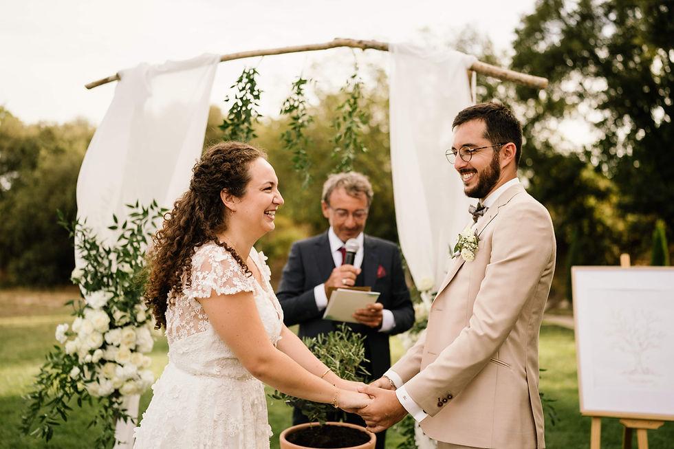 Bride and groom listening to a wedding reading under an arch